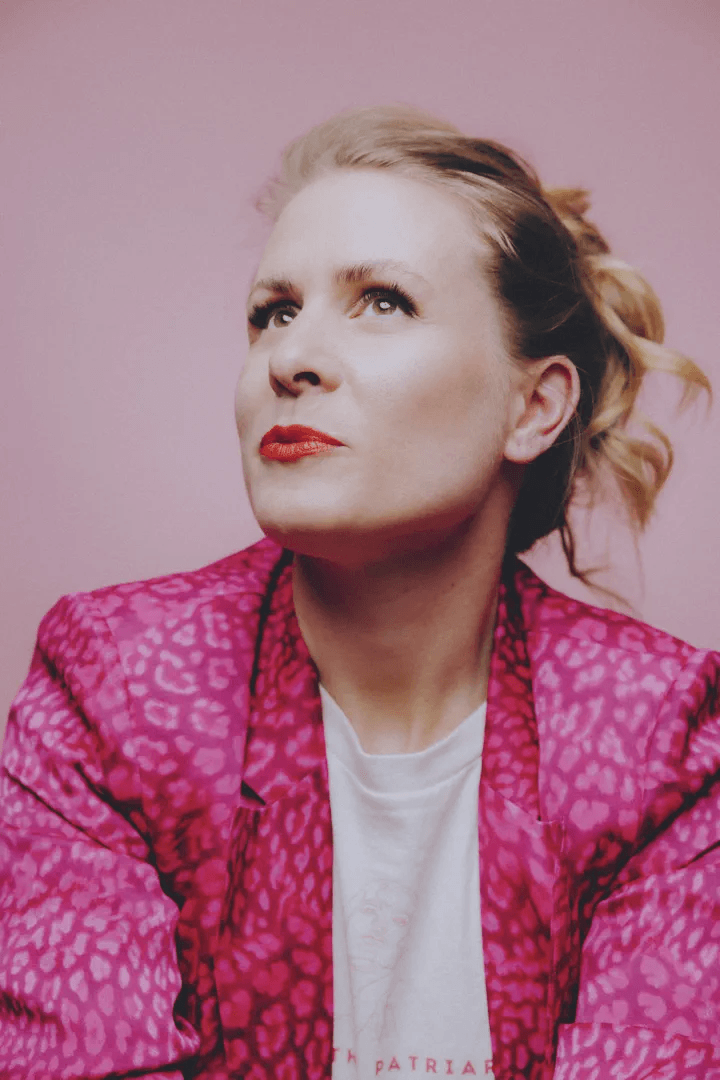 Porträt von Nadine Birner vor rosa Hintergrund – feministische Doula für selbstbestimmt gebären, informierte Entscheidungen und persönliche Begleitung rund um Schwangerschaft und Geburt.
